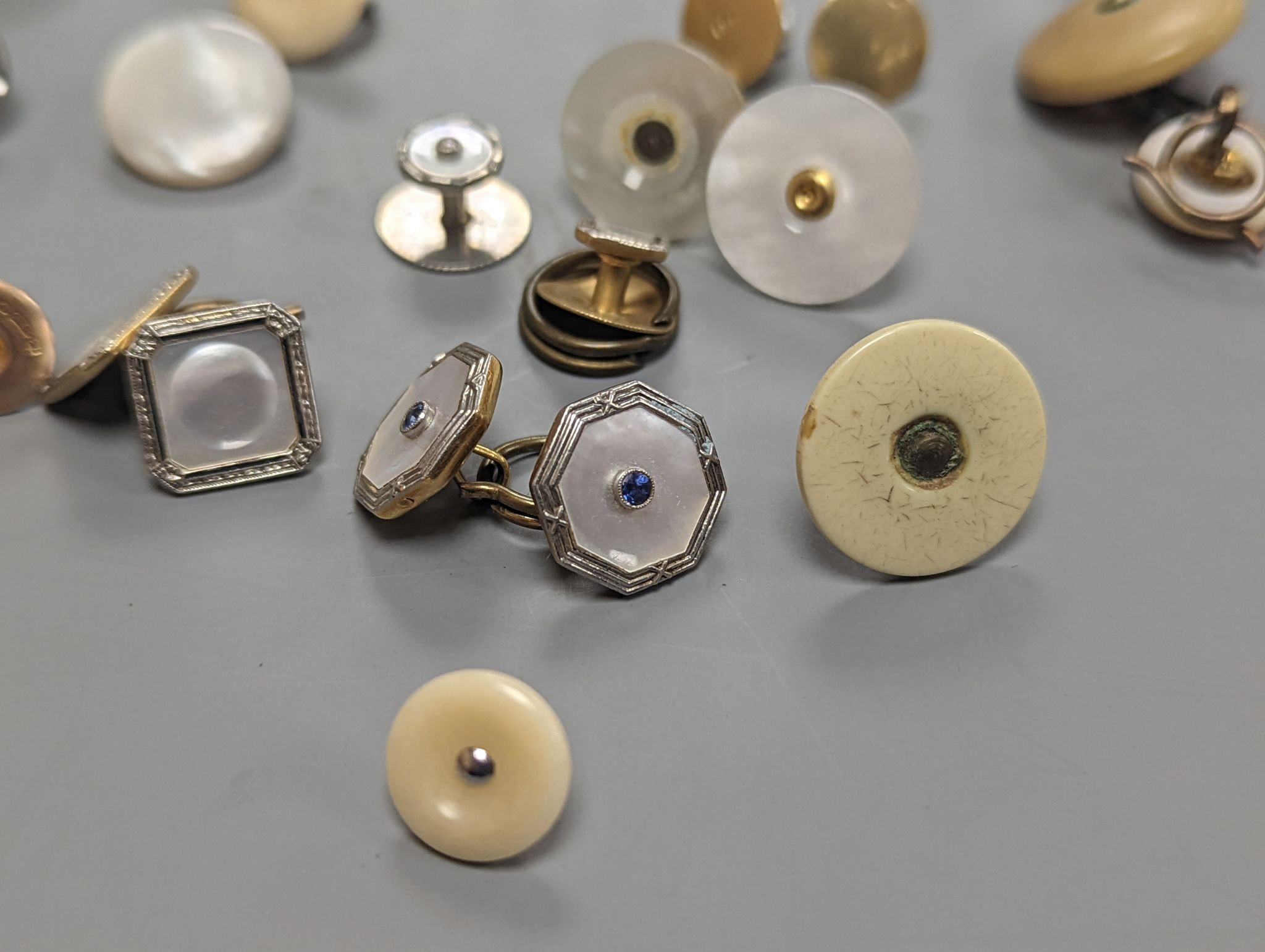 Two pairs of 18ct and mother of pearl cufflinks, one set with sapphires, both with gilt metal associated links, together with a quantity of base metal buttons, cufflinks, studs, etc.
